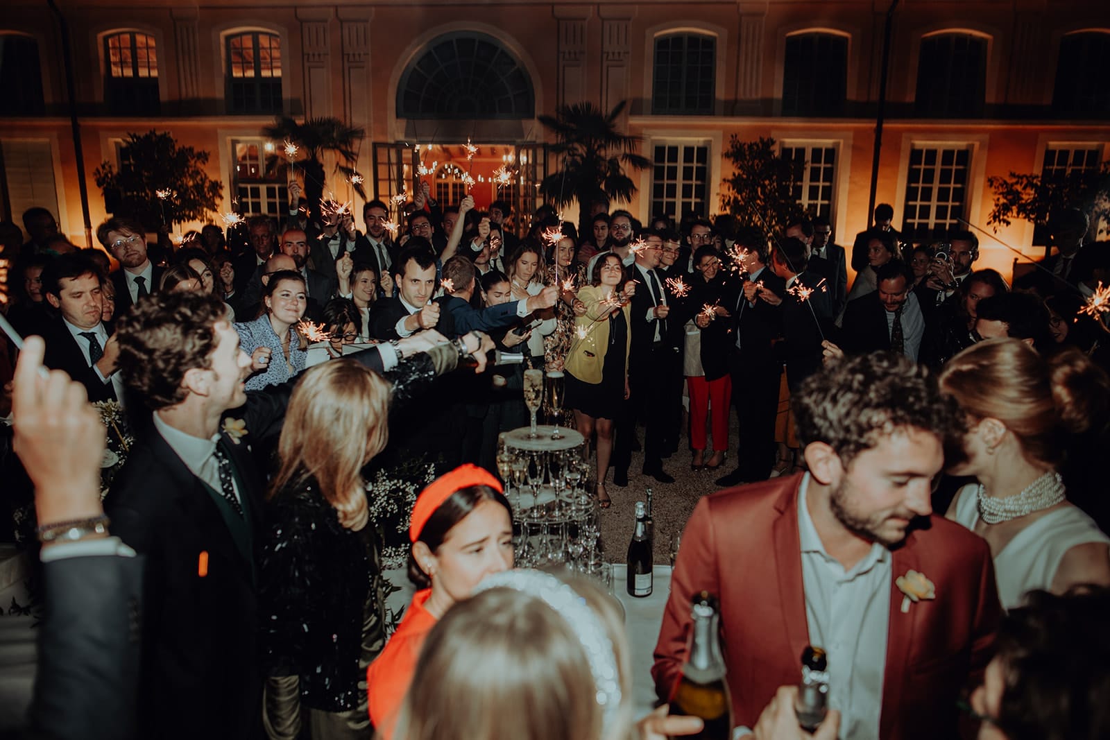 Une foule d’invités réunie autour des mariés, feux de Bengale levés, coupes prêtes et ambiance électrique dans la cour éclairée du domaine – par Castille Alma, photographe de mariage à Chiang Mai, Bangkok et partout en Asie