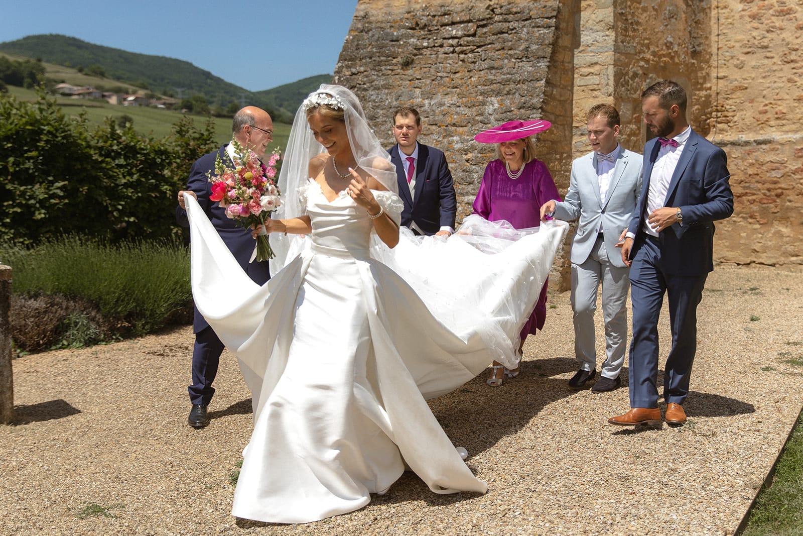 La mariée marche vers l’église de Pierreclos entourée de ses proches – photographe mariage Château de Pierreclos @castillealma