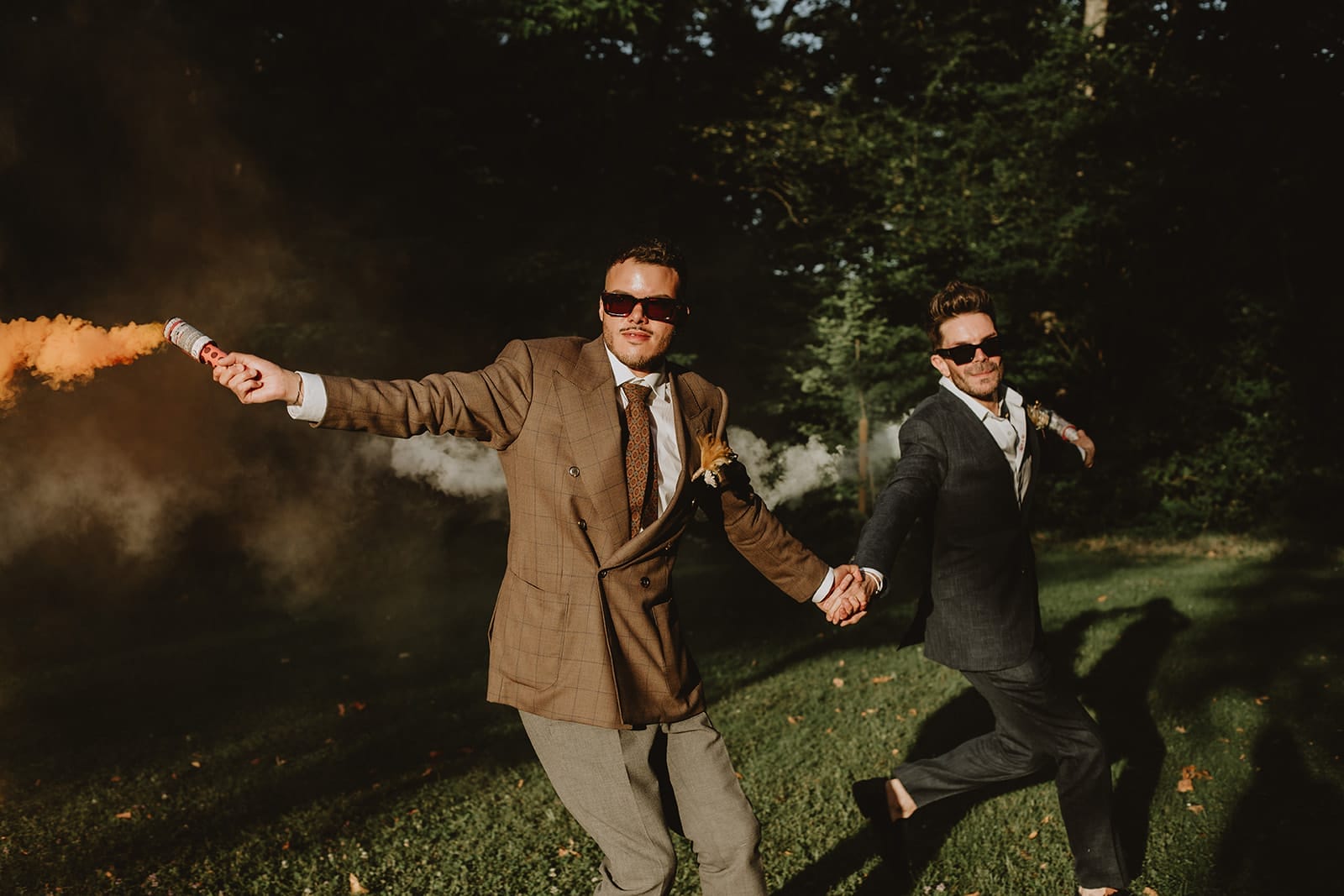 Deux mariés courant main dans la main avec des fumigènes colorés