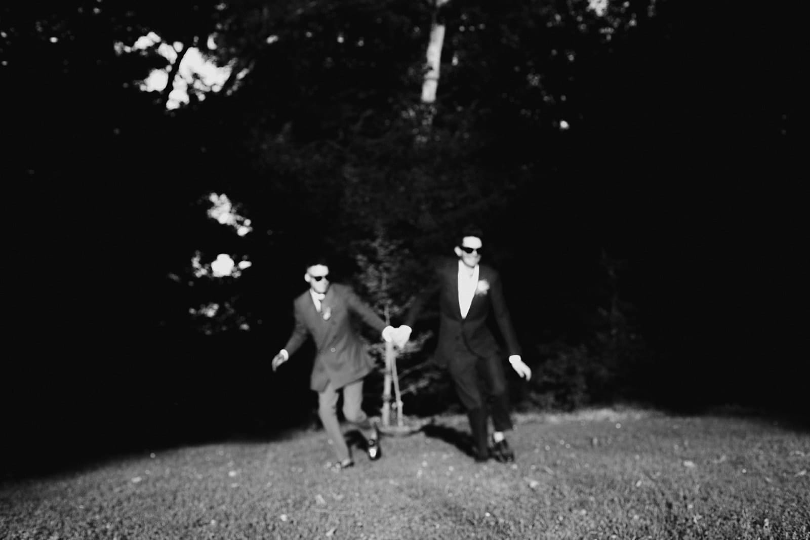 Deux mariés flous courant main dans la main en noir et blanc