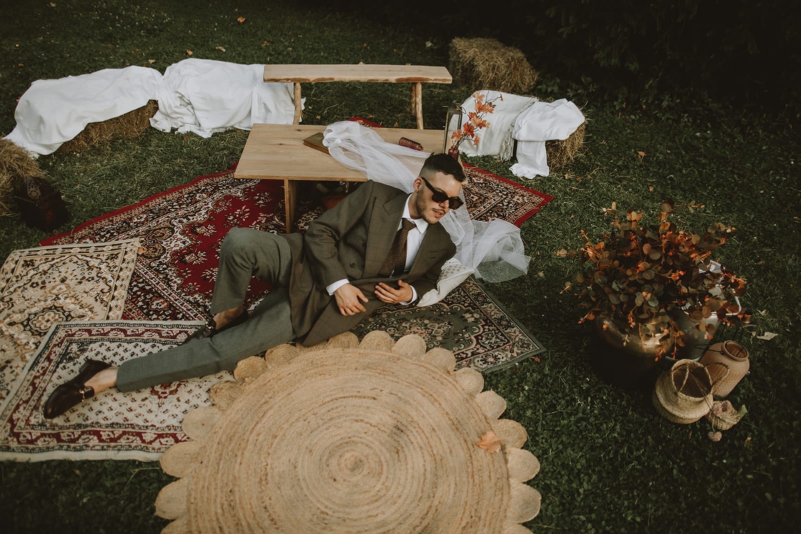 Groom lounging casually on wedding picnic setup, showing how to make wedding group photos fun and relaxed.