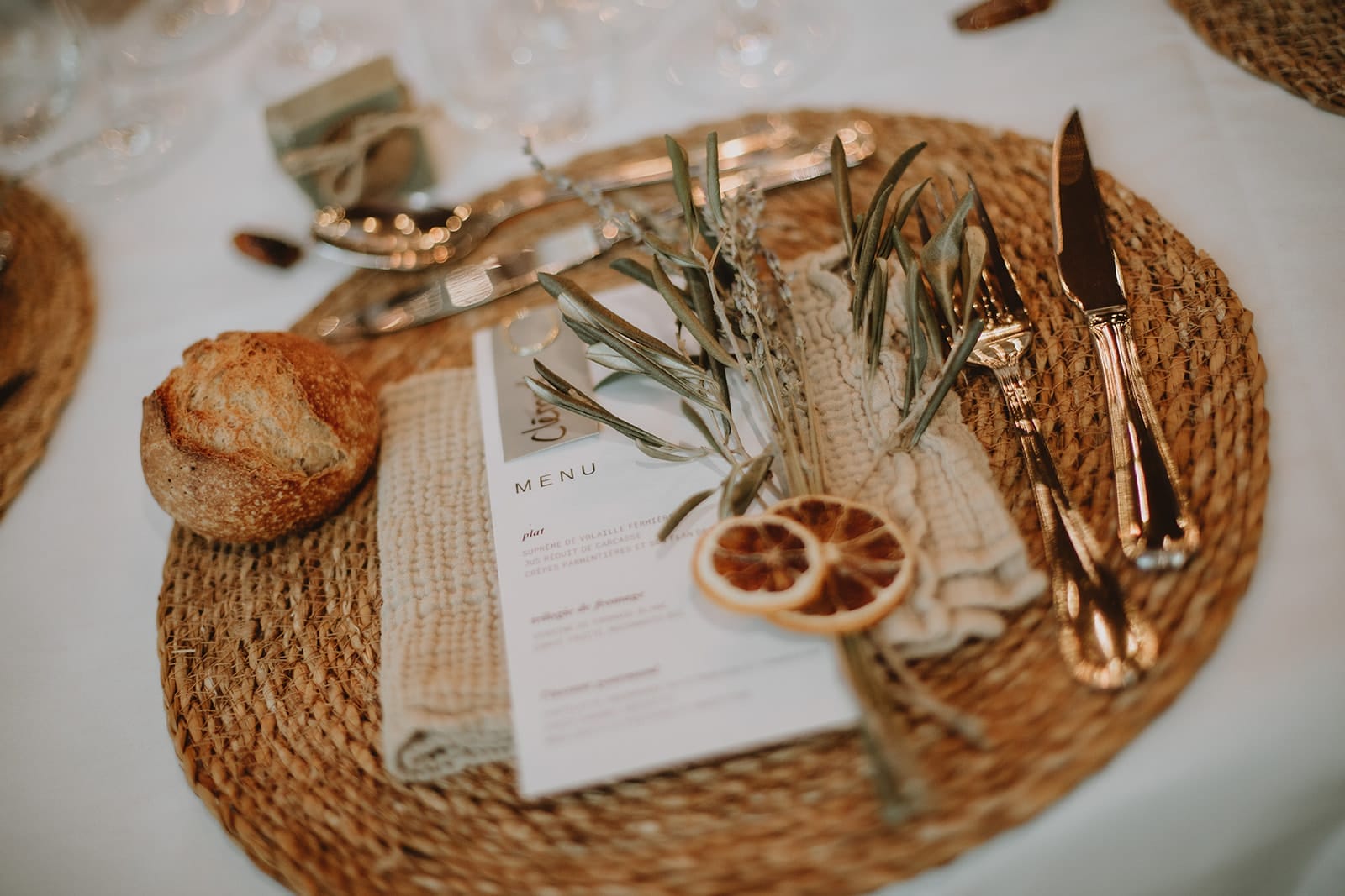 Détail d’un set de table avec menu, pain, herbes et tranche d’orange séchée