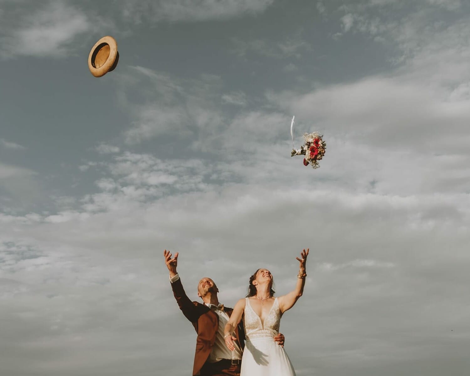 Lancer de bouquet et de chapeau par les mariés sous un ciel nuageux à Ville-sur-Jarnioux