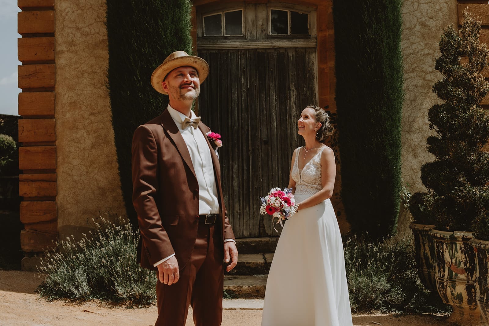 Portrait des mariés sous le soleil au Manoir de la Garde à Ville-sur-Jarnioux – costume brun et bouquet coloré