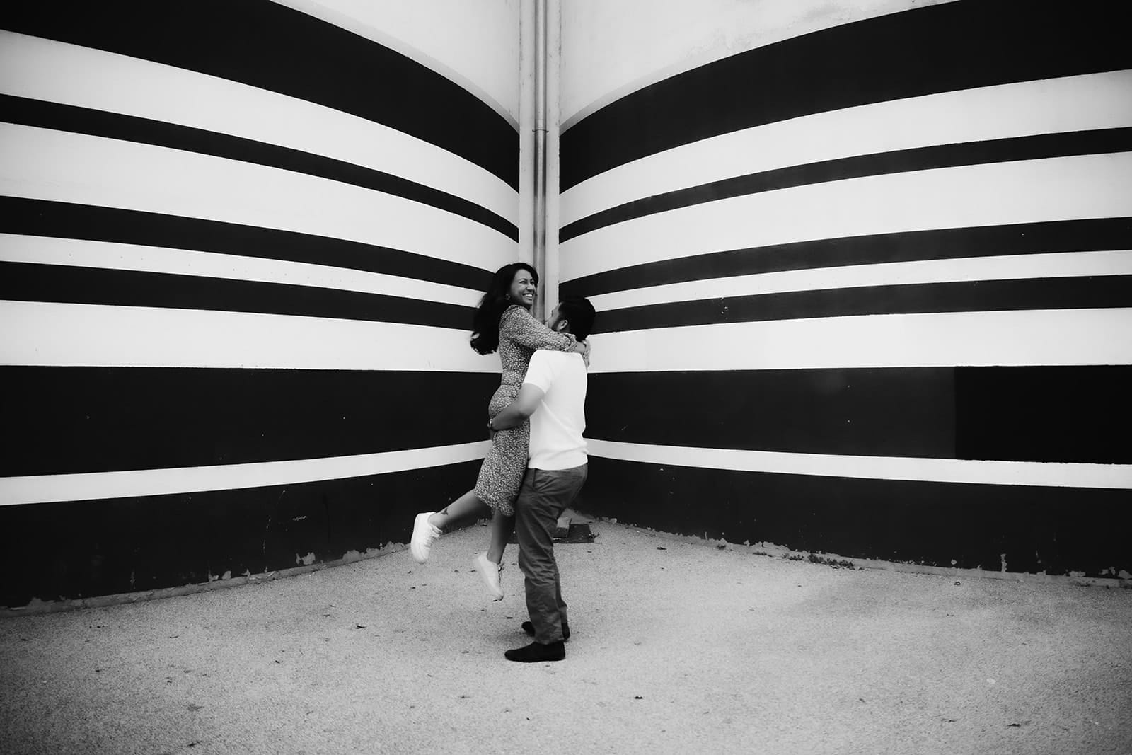 Couple qui rit pendant une séance engagement à Lyon devant un mur graphique