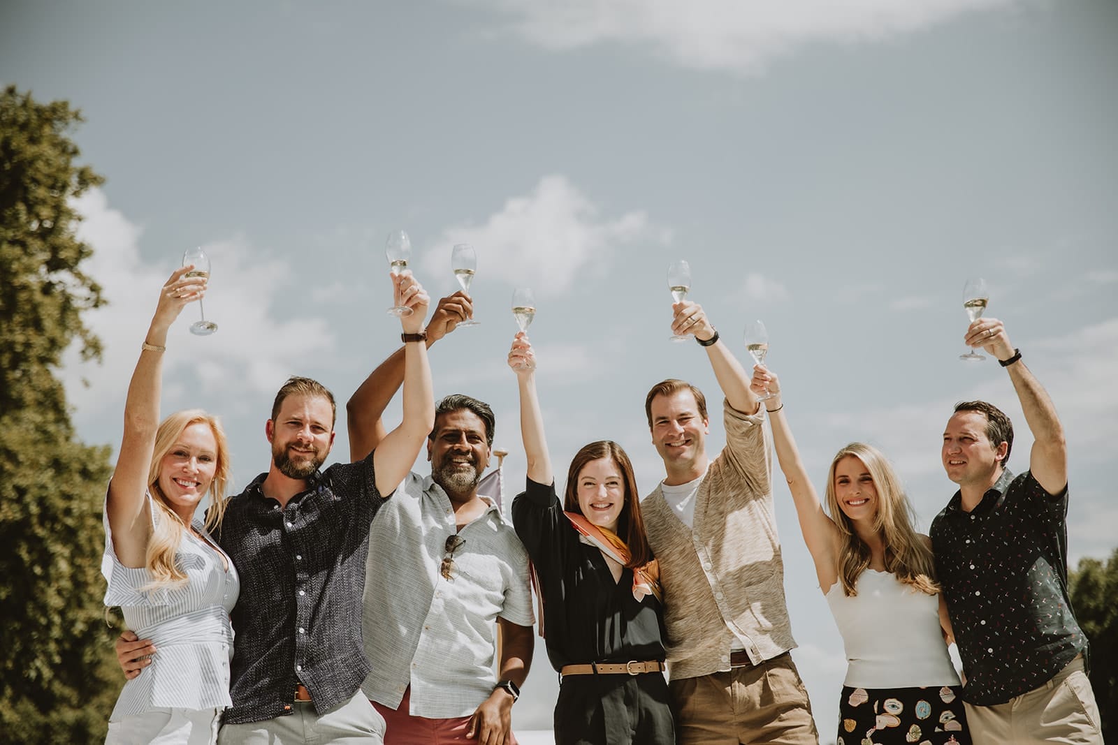 Group of friends raising glasses under the sun during a toast in Lyon