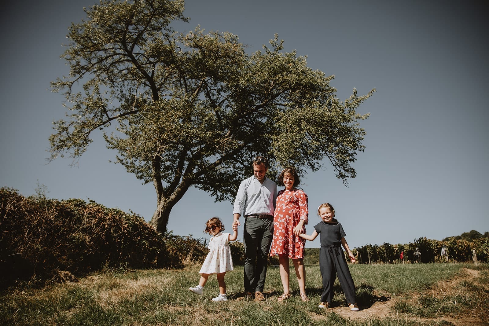 Une famille heureuse se tient la main dans un champ verdoyant.