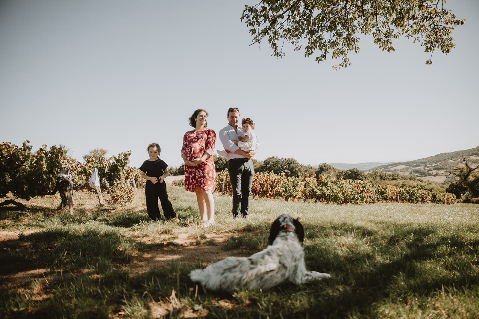 Une famille joyeuse posant dans un vignoble ensoleillé.