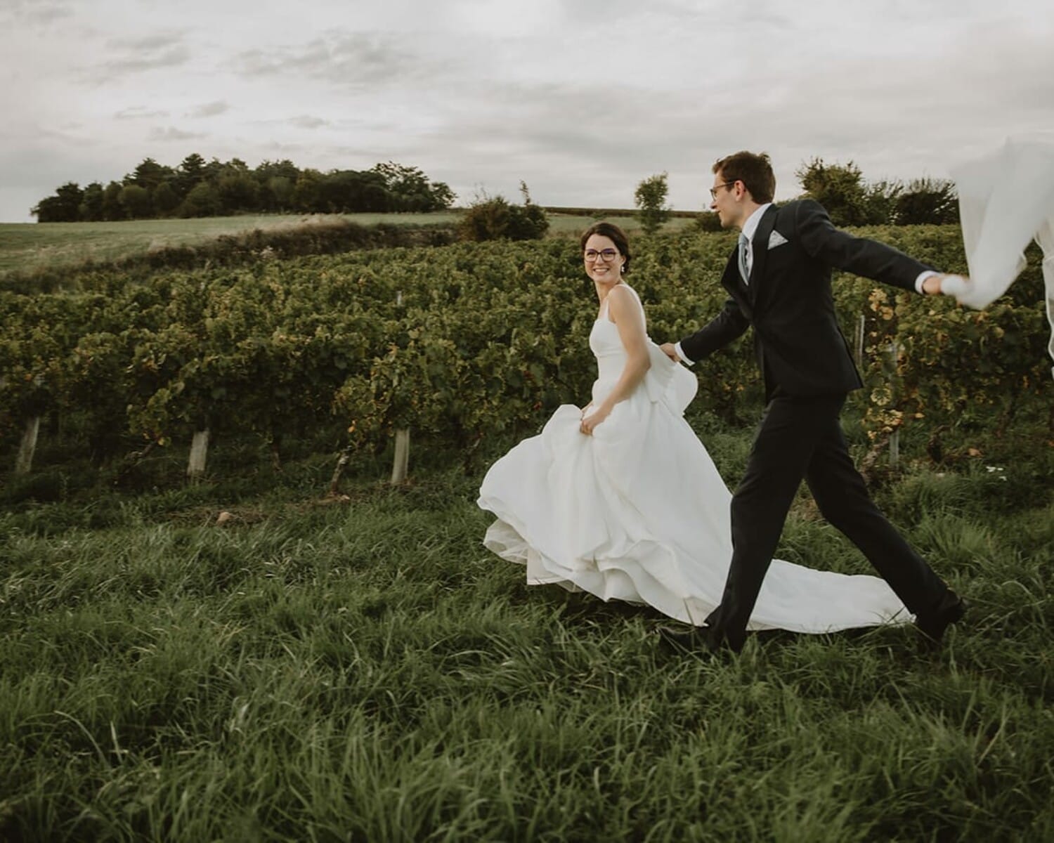 Un couple joyeux dans un vignoble à Lyon, vêtus de leurs habits de mariage.