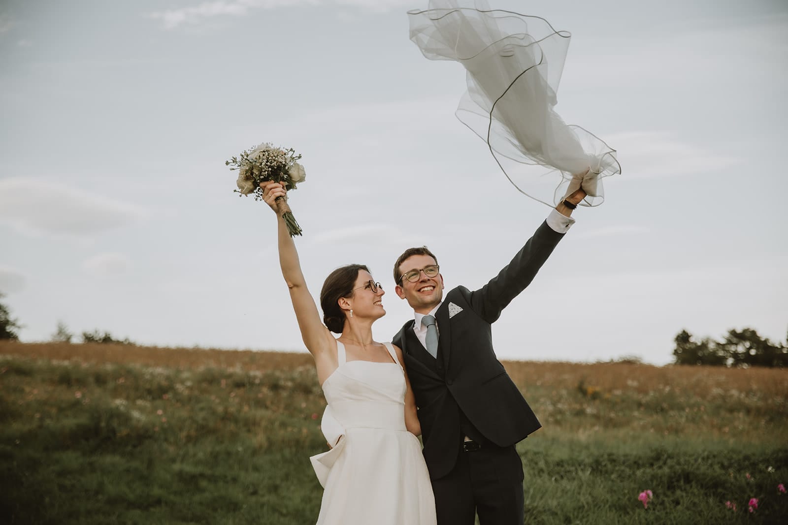 Un couple rayonnant célèbre leur mariage dans un champ verdoyant.