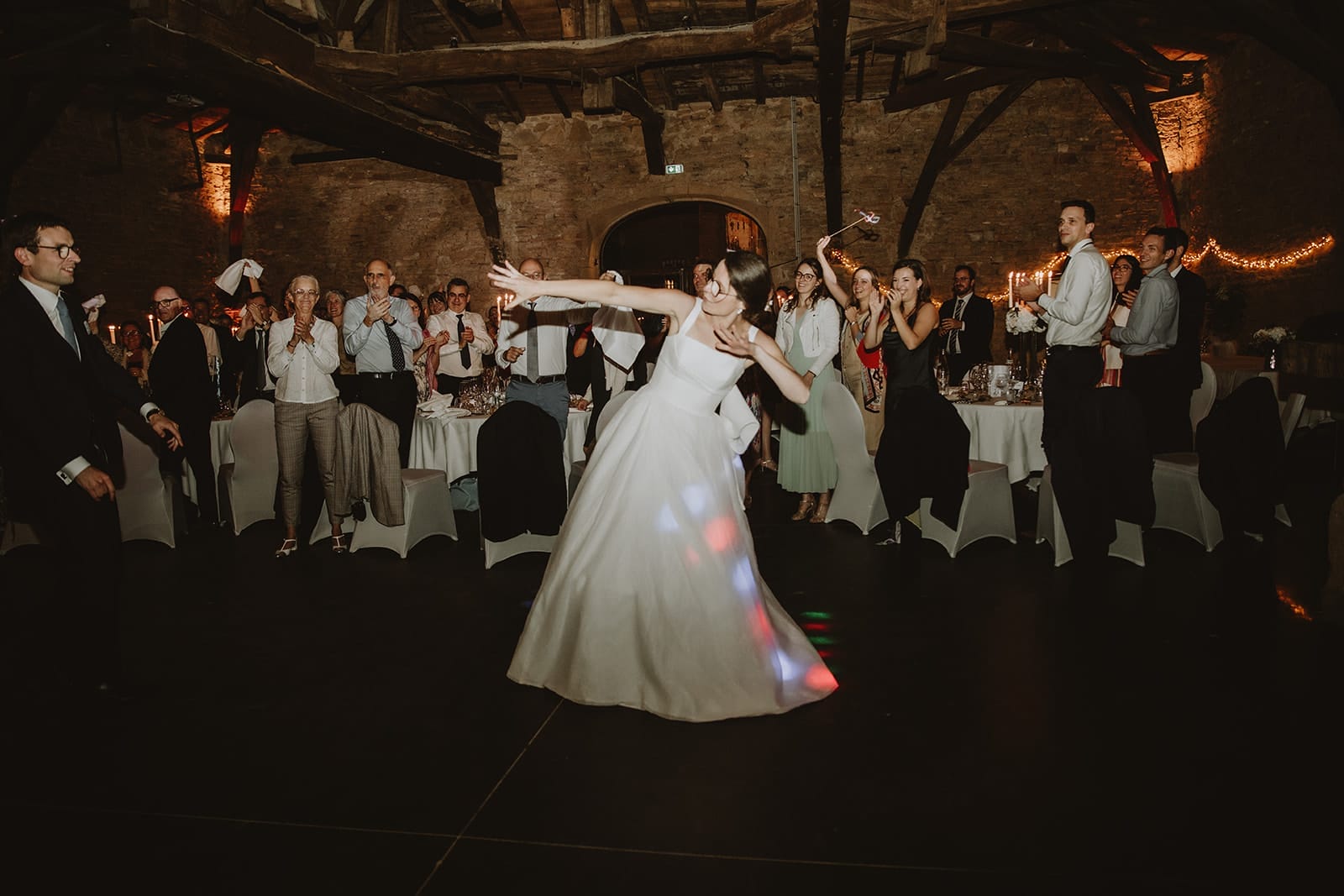 Une mariée s'épanouit sur la piste de danse, entourée d'invités émerveillés.