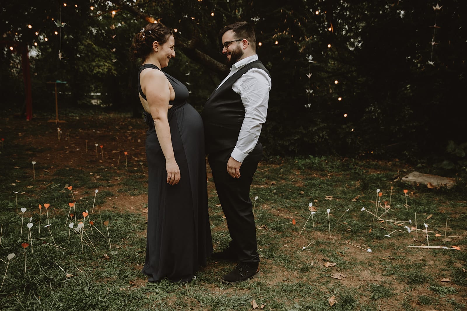 Un couple souriant se regarde tendrement dans un jardin à Lyon.