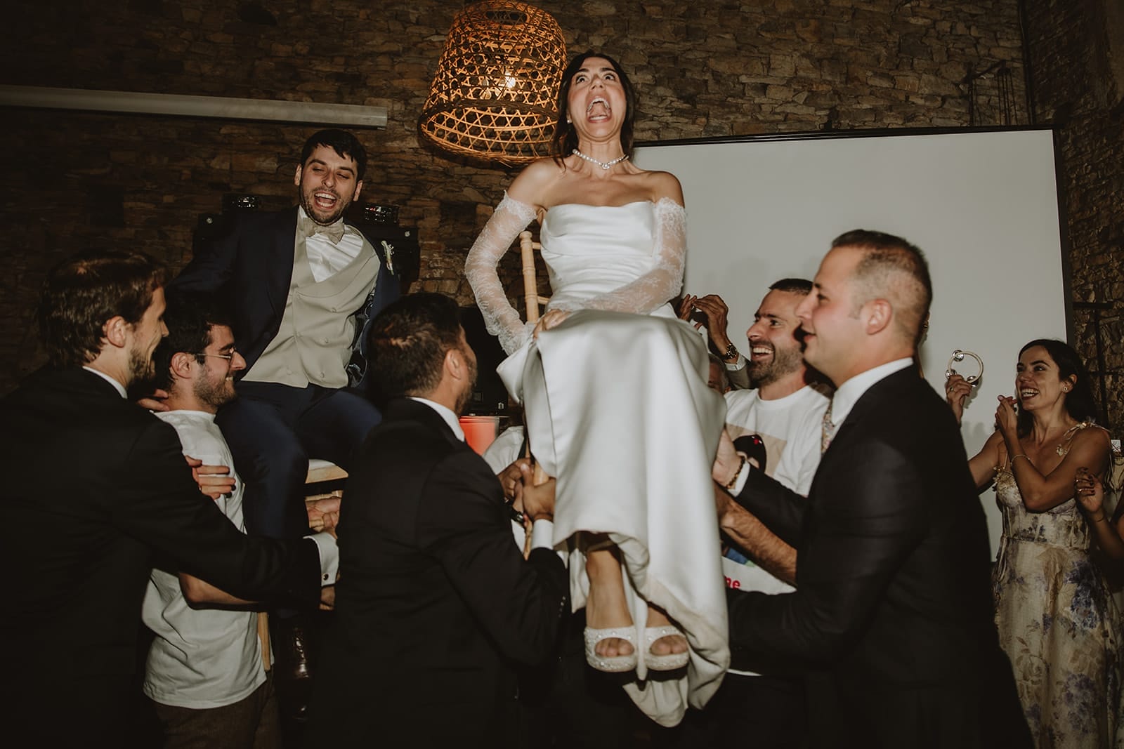 Une mariée souriante portée par ses amis lors d'une fête à Lyon.