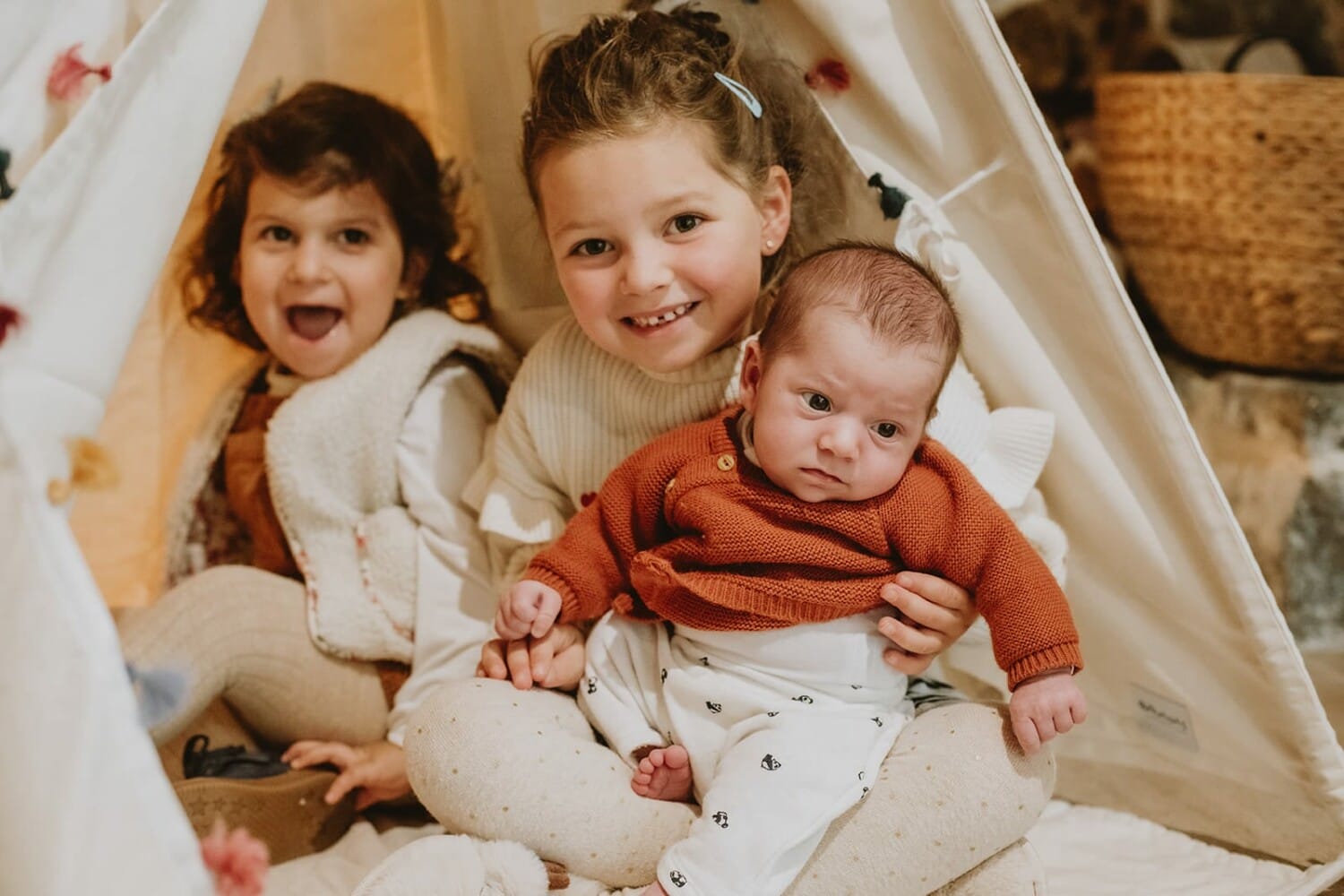Trois enfants joyeux dans un tipi, créant des souvenirs chaleureux.